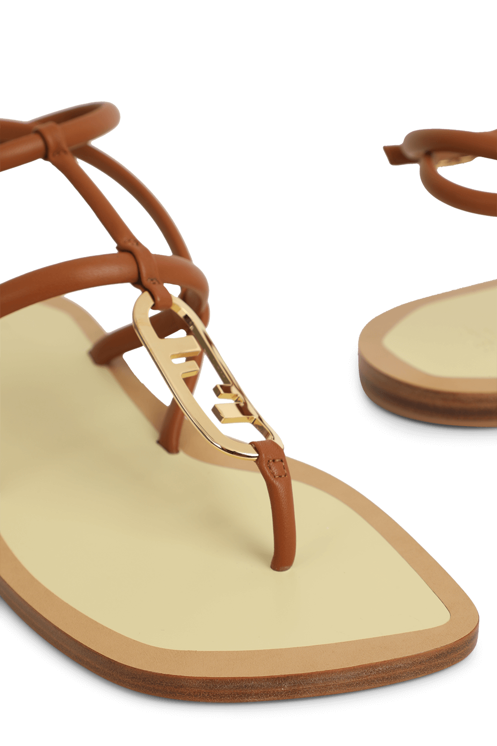 תמונת תקריב של סנדלי רצועות עור חום עם לוגו מוזהב