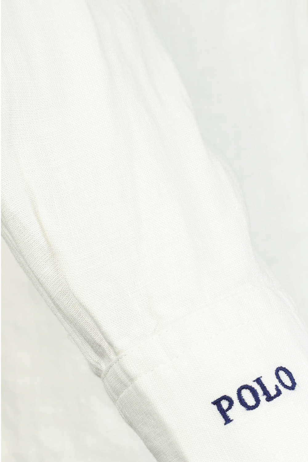 תמונת תקריב של חולצת פשתן ארוכה לבנה עם לוגו רקום