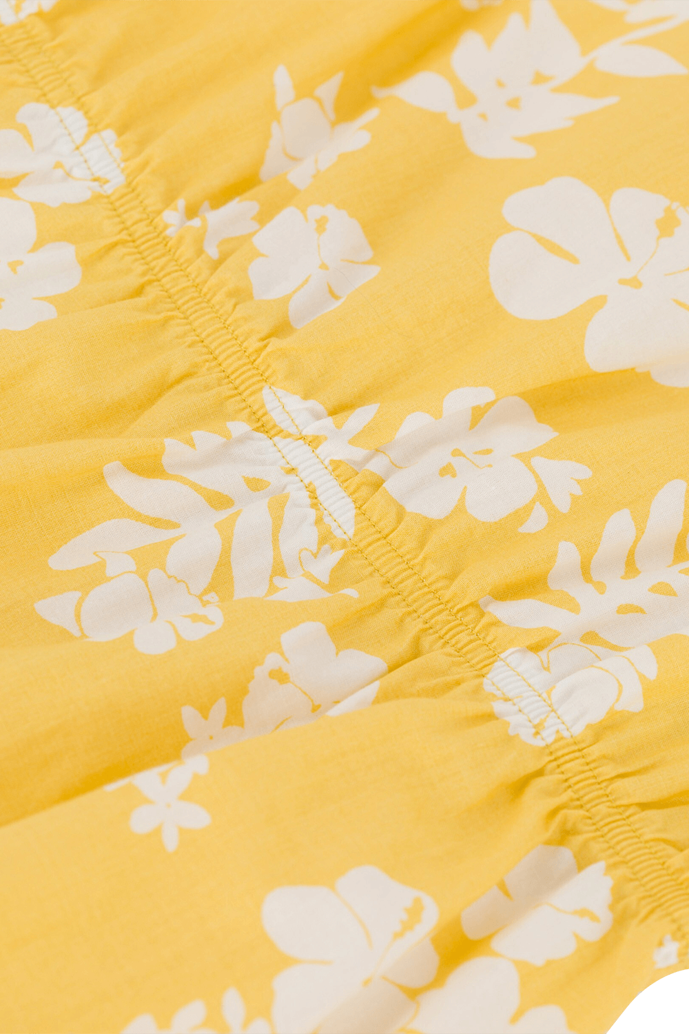 תמונת תקריב של גילאי 6-12 חודשים אוברול קצר צהוב עם בוטני פרחים לבן