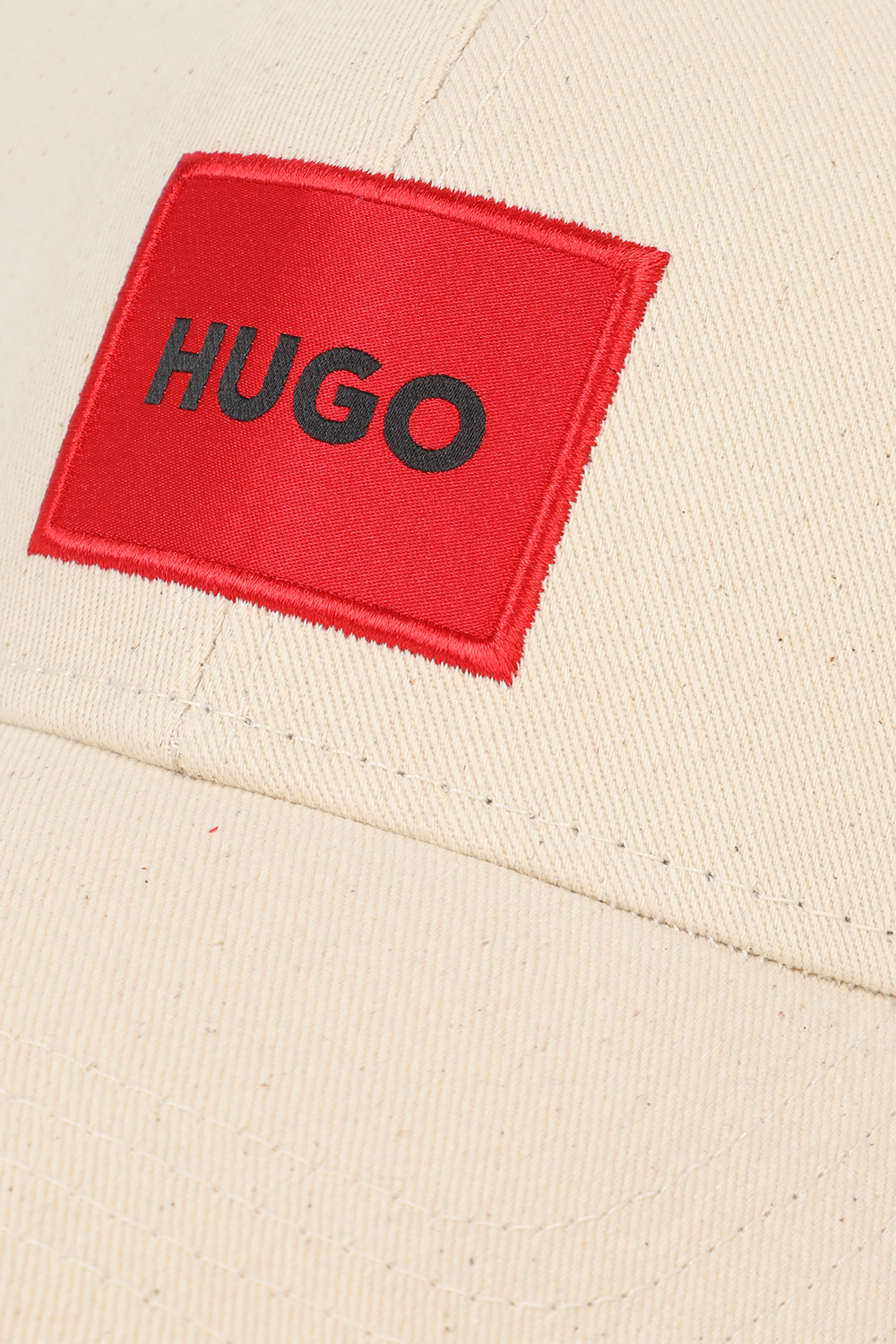 תמונה אחורית של כובע בייסבול שמנת עם תגית לוגו אדומה