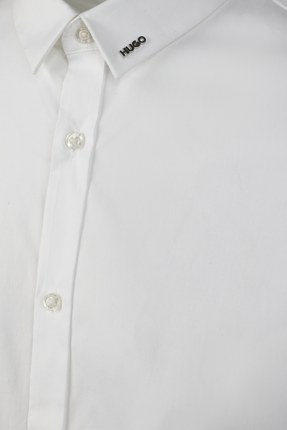 תמונה אחורית של חולצה מכופתרת עם לוגו מטאלי