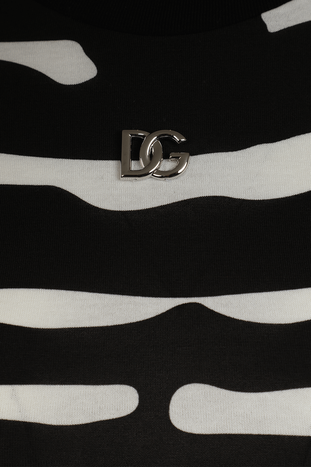 תמונת תקריב של חולצת קרופ בהדפס זברה עם לוגו מטאלי